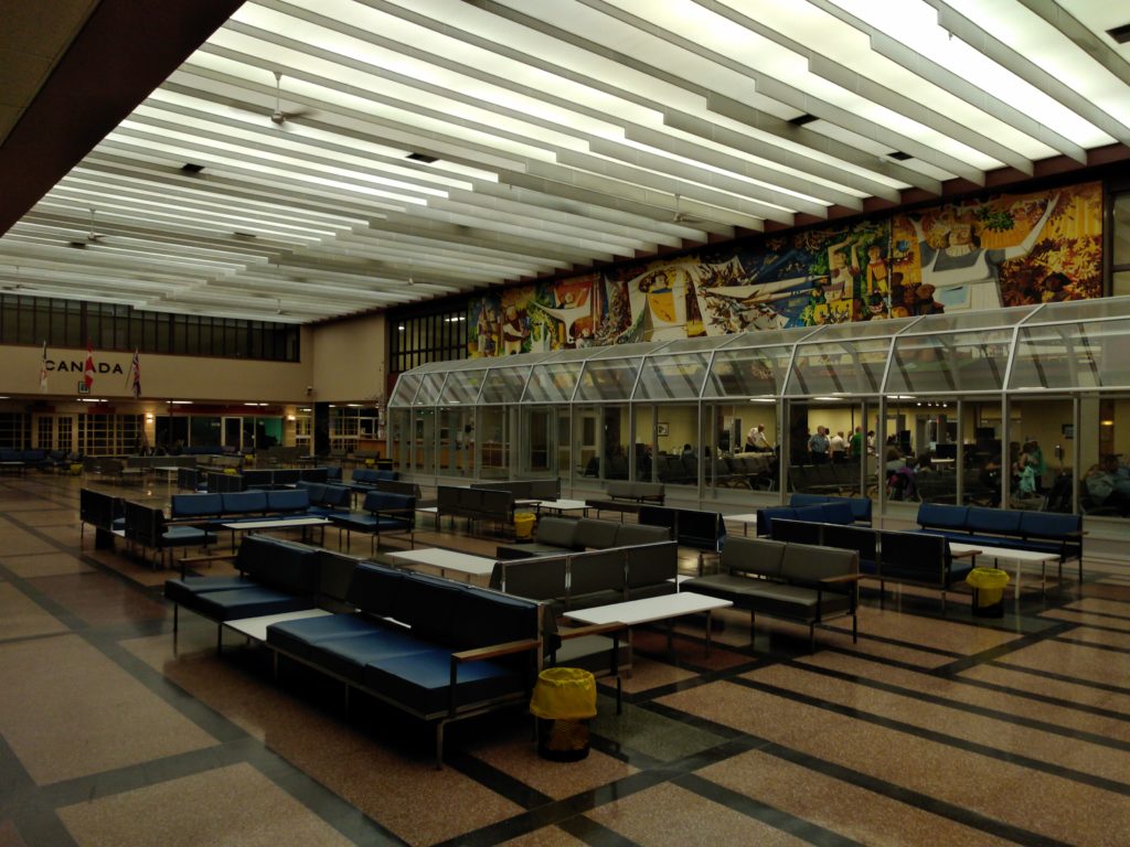 Gander Airport International Terminal looking at the blue chairs used by passengers and the Art Deco mural, Flight and Its Allegories by Ken Lochhead