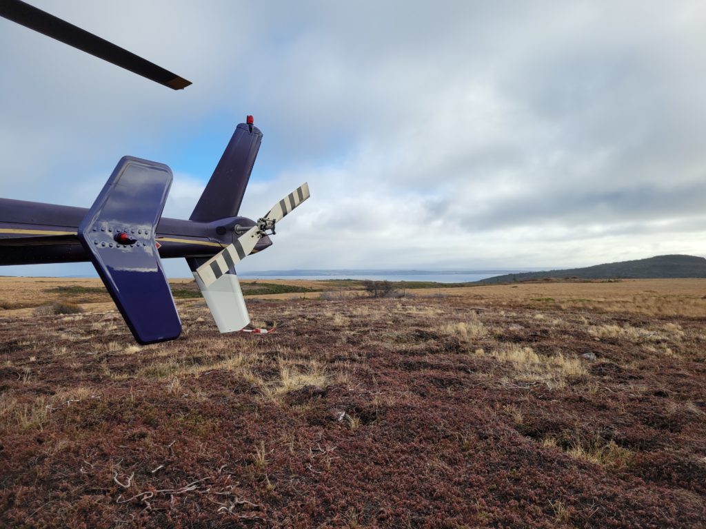 The tail of a helicopter with barrens and hills in the background
