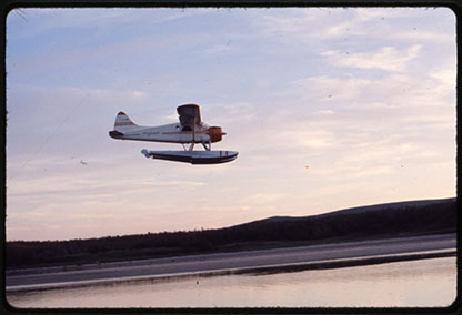 A float plane flying over a pond.