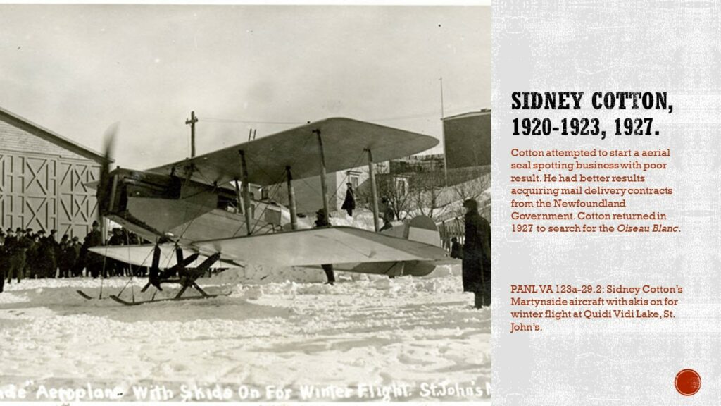 Black and white photo of an aircraft on skis on show with the propeller turning. There is a hangar in the background, and the bottom of a St. John's street. 

Text reads: Sidney Cotton, 1920-1923, 1927. Cotton attempted to start an aerial seal spotting business with poor results. He had better results acquiring mail delivery contracts from the Newfoundland Government. Cotton returned in 1927 to search for the Oiseau Blanc.

Caption: PANL VA 123a-29.2: Sidney Cotton's Martynside aircraft with skis on for winter flights at Quidi Vidi Lake, St. John's.